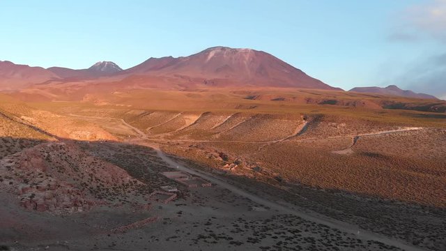 Aerial cinematic shot near the ground approaching a volcano at golden hour in the Atacama Desert, Chile, South America