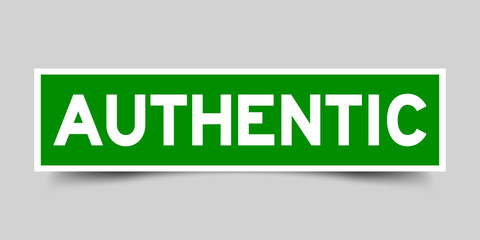 Green and white sticker with word authentic on gray background