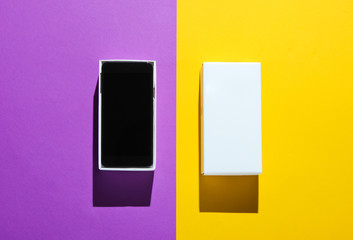 New smartphone in open box on colored paper background. Top view, minimalism