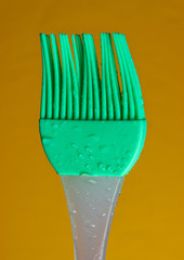 Silicone kitchen brush for cooking in drops of water on yellow background