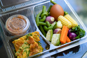 Various kinds of blanched vegetables, omelet, cha-am, and chili paste beautifully arranged in clear plastic boxes. and look modern