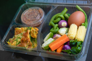 Various kinds of blanched vegetables, omelet, cha-am, and chili paste beautifully arranged in clear plastic boxes. and look modern