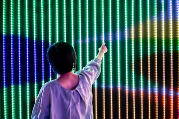 Asian woman playing with led light interaction wall