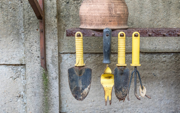 A Row Of Yellow And Black Metal Hand Gardening Tools Isolated Hanging From Spikes With A Gap For A Missing Tool Image With Copy Space