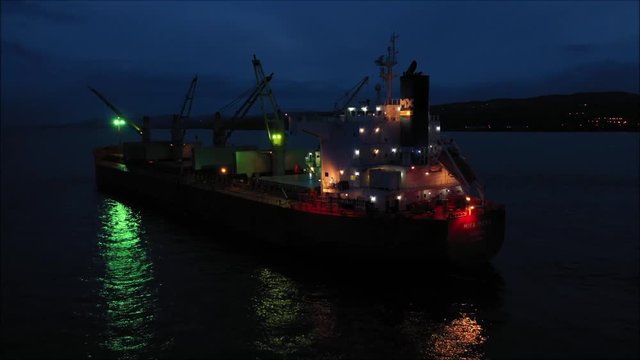 Bulk carrier cargo ship anchored on Lough Foyle at night off loading coal into adjacent cargo vessel called 'lightening work', captured by drone.