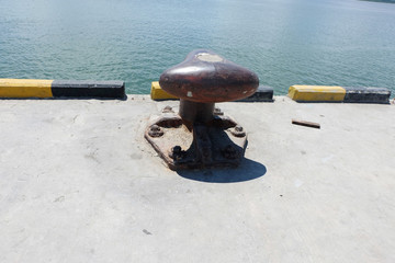 Rusty mooring bollard with ship ropes