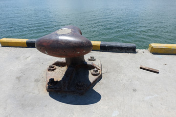 Rusty mooring bollard with ship ropes