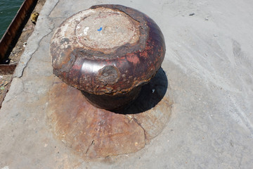 Rusty mooring bollard with ship ropes