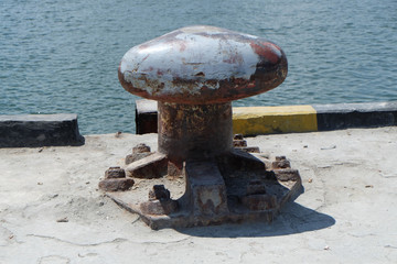 Rusty mooring bollard with ship ropes