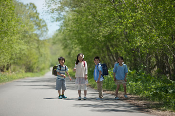 Obraz premium 一本道で微笑む小学生