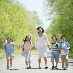 一本道を歩く小学生と先生