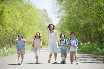 一本道を歩く小学生と先生