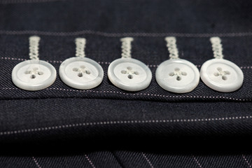 Bespoke jacket selective focused on sleeve buttons,side view..Close up detail of five sleeve  buttons and stitching for custom made jacket with pinstripe pattern fabric, professional tailor concept.