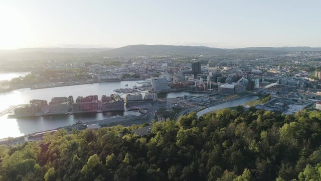 4K aerial of the Oslo city line with backdrop of Oslo and the construction of Bjoervika, a popular tourist attraction with the Munch museum, Barcode and Soerenga pier, in sunset with backward motion.