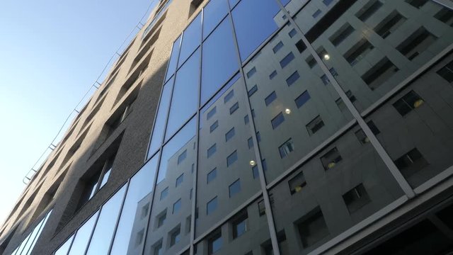 4K video with pan motion of the exterior facade of a financial office building in the Barcode quarter of Bjoervika in Oslo, with reflections of another building in the blue/dark windows.