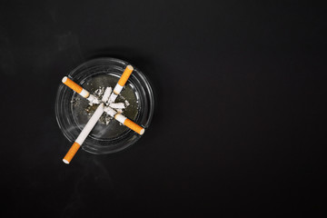 cigarette cross in ashtray, dark background. World No Tobacco Day concept. Smoking kills. Copy space