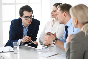 Group of business people discussing questions at meeting in modern office. Managers at negotiation or brainstorm. Teamwork, partnership and business concept