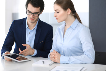 Businessmen and woman using tablet computer in modern office. Colleagues or company managers at workplace. Partners discussing contract. Business concept