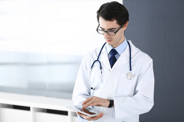 Doctor man using tablet computer for network research or virtual disease treatment. Perfect medical service in clinic. Modern  medicine, medic data and healthcare concepts