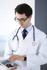 Doctor man using tablet computer for network research or virtual disease treatment. Perfect medical service in clinic. Modern  medicine, medic data and healthcare concepts