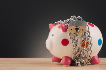 financial crisis or economic depression concept, piggy bank surrounded by chains  and padlock on wooden desk