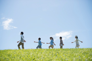 草原を歩く小学生と先生