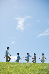 草原を歩く小学生と先生