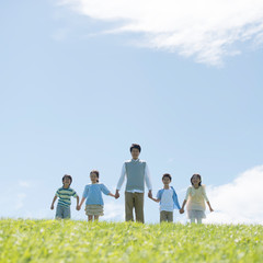 草原で手をつなぐ小学生と先生