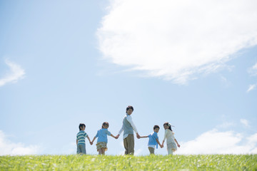 草原で手をつなぐ小学生と先生