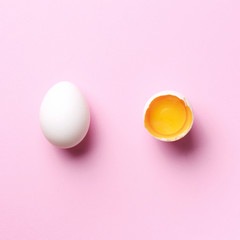 Food concept with broken egg and whole one on pink background. Top view. Creative pattern in minimal style. Flat lay. Square crop