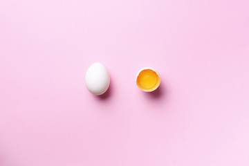 Food concept with broken egg and whole one on pink background. Top view. Creative pattern in minimal style. Flat lay