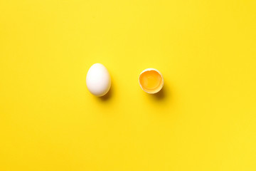 Food concept with broken egg and whole one on yellow background. Top view. Creative pattern in minimal style. Flat lay.
