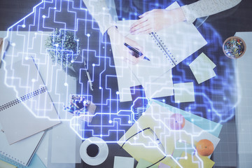 Double exposure of writing hand on background with brain hologram. Concept of learning.