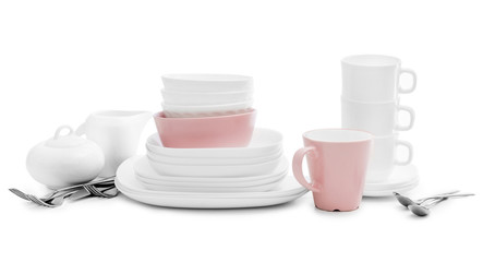 White and pink plates, sugar bowl and mugs on light background