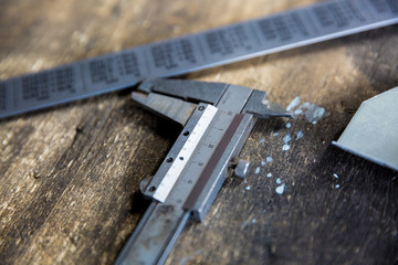 Vernier caliper and metal meter ruler on oil stained table, measuring tool