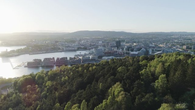 4K aerial of the Oslo city line with a backdrop of Oslo and Bjoervika, a popular tourist attraction with the Munch museum, Barcode, Opera and Soerenga pier, in a sunset with pan motion.