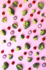 Creative layout of green broccoli, tomatoes, onion on pink paper background. Top view. Food pattern in minimal style.