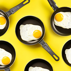 Creative food pattern with fried eggs on pans over yellow background. Top view. Creative pattern in minimal style. Flat lay. Square crop