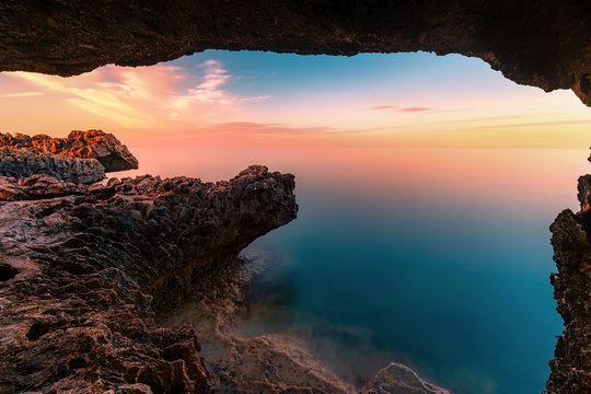 Amazing sunset image of Cape Greco cliffs and rocks on a sunset in Paralimni, Cyprus. Colorful red, pink and yellow skies with turquoise blue sea. 