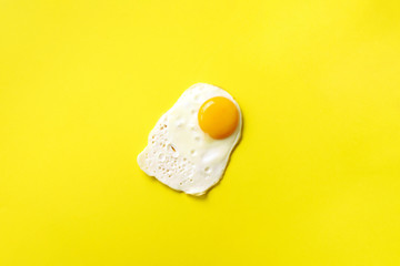 One fried egg on yellow paper background. Creative food concept in minimal style. Top view
