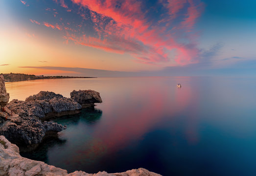 Amazing sunset image of Cape Greco cliffs and rocks on a sunset in Paralimni, Cyprus. Colorful red, pink and yellow skies with turquoise blue sea. 