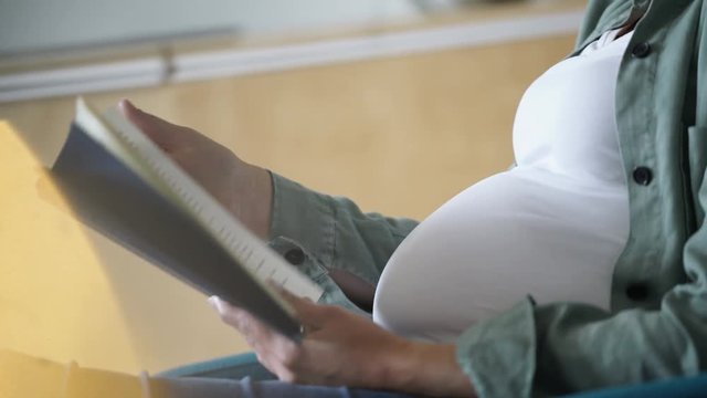 Closeup of pregnant woman reading a book and relaxing