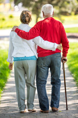 Cheerful senior couple having good time in city park, walking, laughing and enjoying sunny day