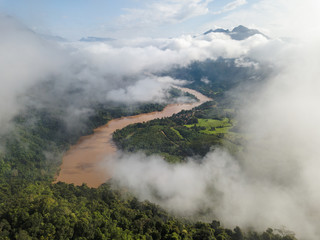 Fototapeta premium View from the top Viewpoint of Nong Khiaw, Laos. Stunning scenery with lush green mountains and mysterious clouds.