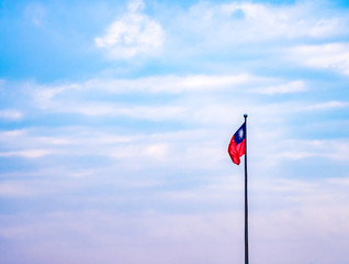 Closeup Taiwan nation flag waving on a pole with colorful pastel sky and clouds.