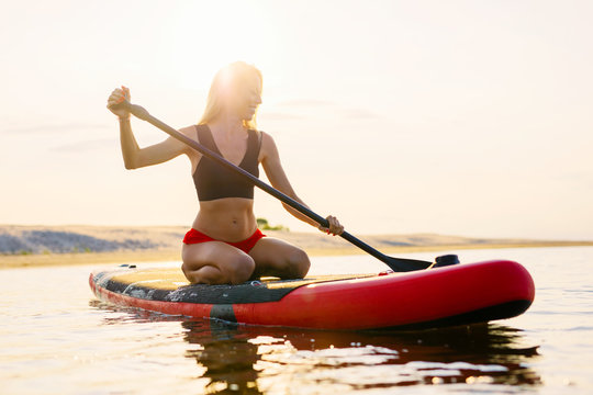 Happy Woman On Paddle Board At Sunset