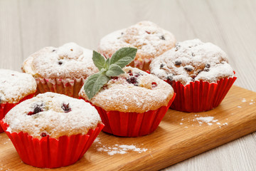 Homemade fruit muffins sprinkled with powdered sugar and mint.