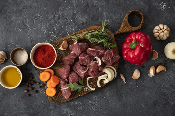 Сut of meat with vegetable on a dark background top view