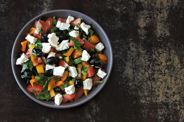 Colorful healthy salad bowl with vegetables, black olives and feta cheese.