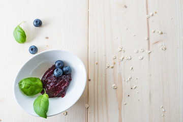 Jam from blueberries in a bowl on a wooden table. For a good delicious breakfast.